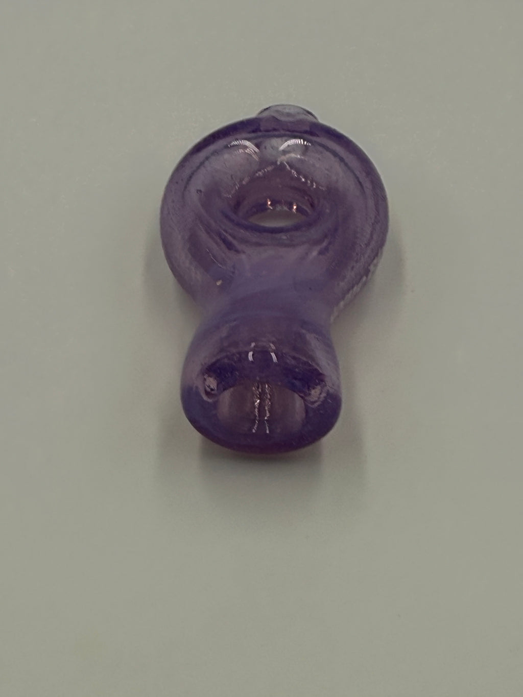A small translucent purple glass pipe with a bulbous, rounded shape, photographed on a plain light gray background.